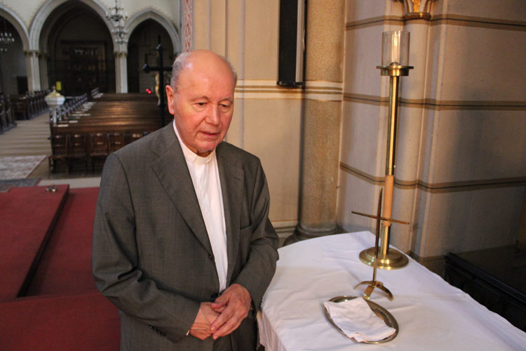 Pfarrer Franz Fischer neben dem beschädigten Messingkruzifix, auf dem zuvor eine Jesusfigur montiert war. 