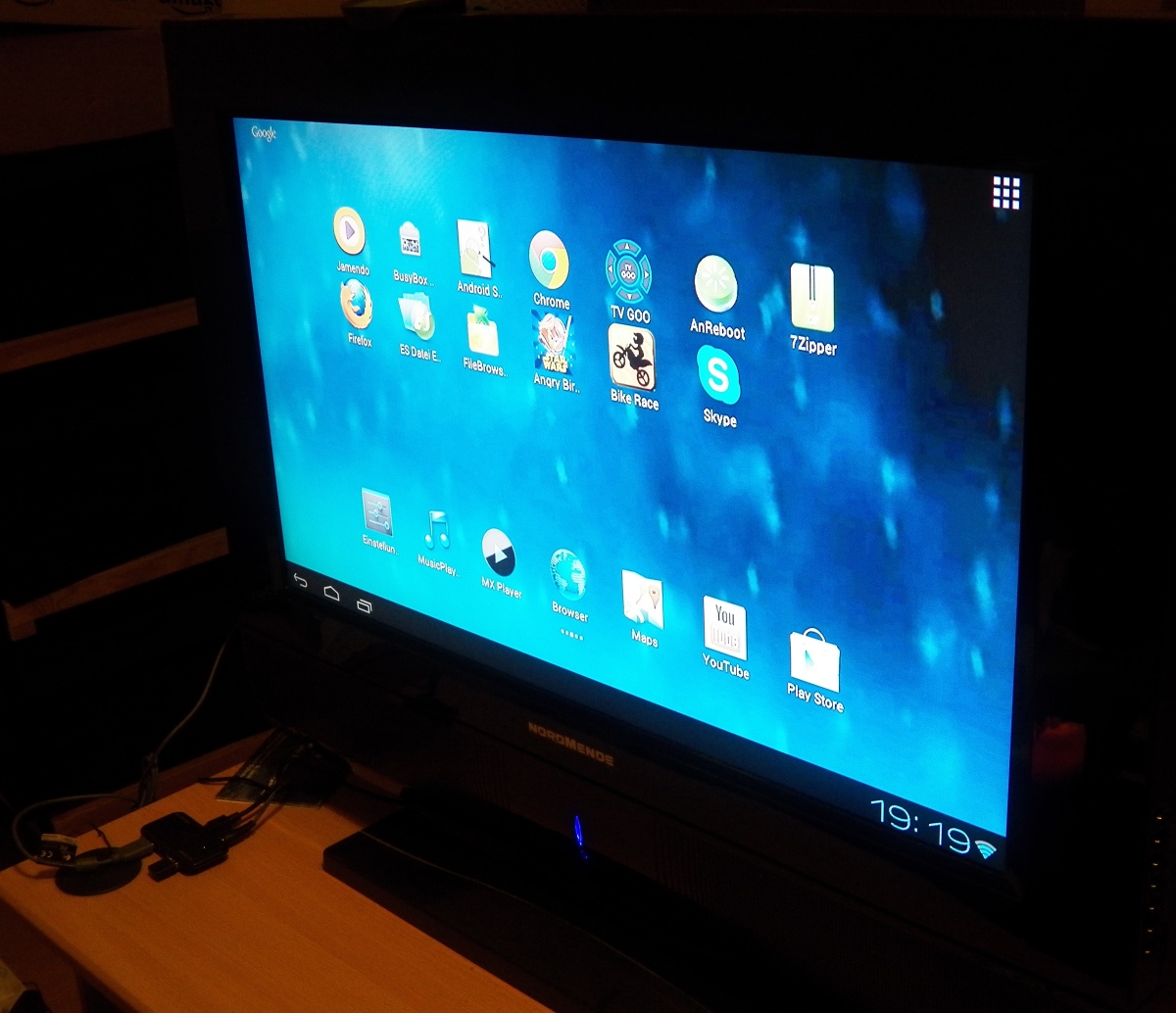 Das TV-Test-Setup. Ein 26 Zoll LCD-Fernseher aus 2009 ohne jeglicher SmartTV-Kapazitäten oder USB-Anschluss. Dazu ein aktiver Hub, über den der Air Remote-Empfänger und eine Logitech-Webcam betrieben und externe Festplatten und andere USB-Datenträger angeschlossen werden können.